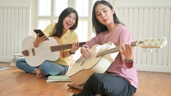 Asian teenage girls are singing and playing guitars.They stay at